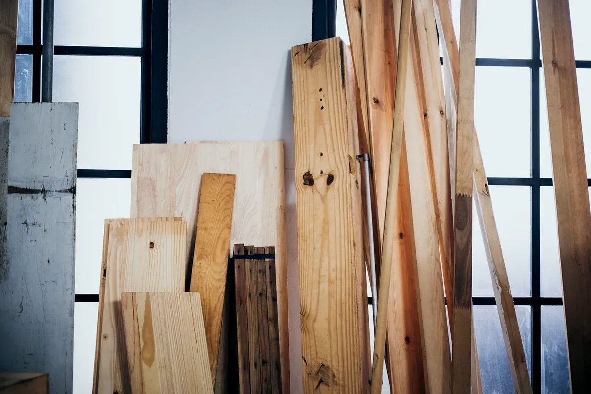 Wood planks of varying sizes stacked against a wall.