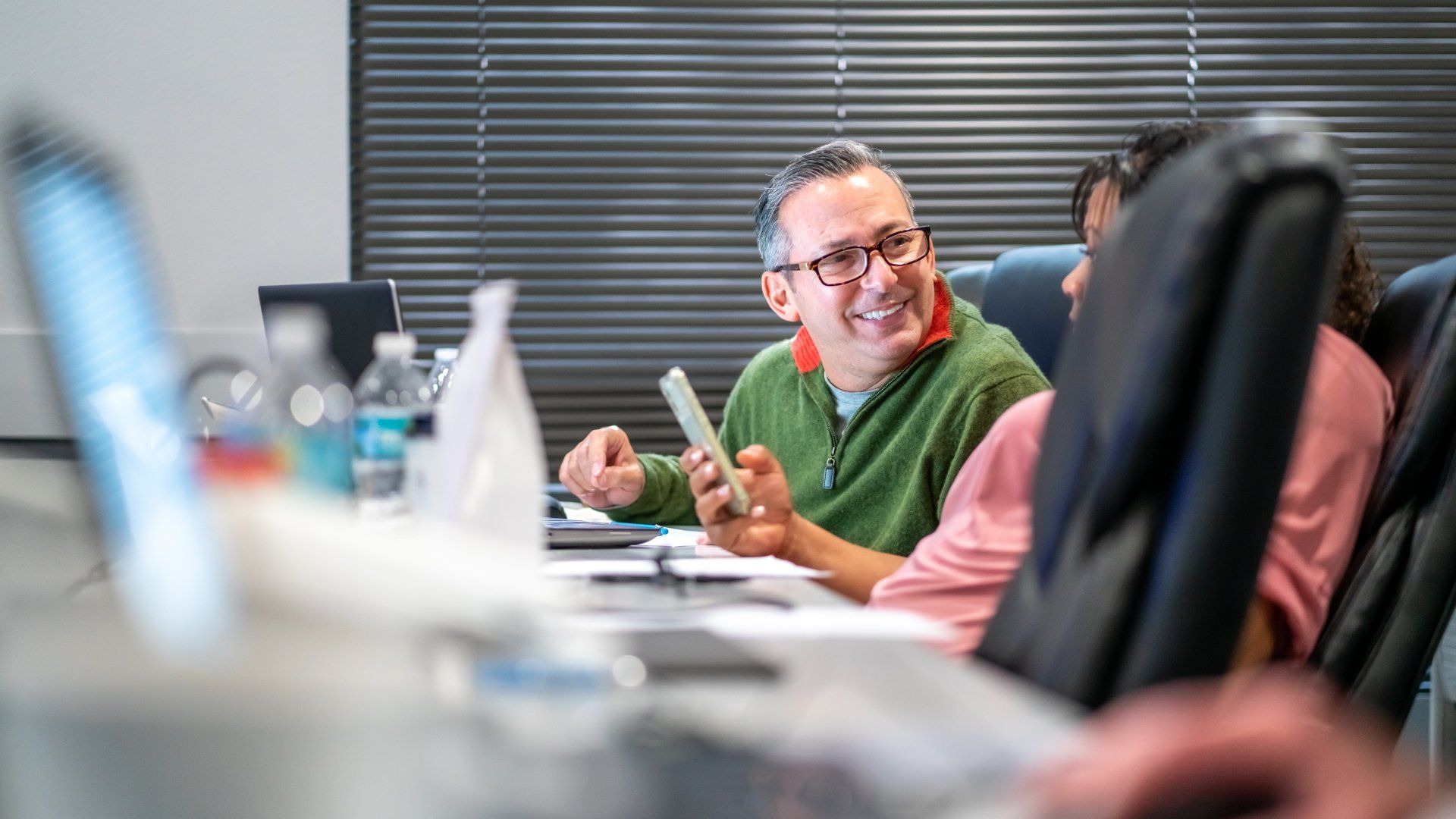A group of people are sitting at a table in a conference room.