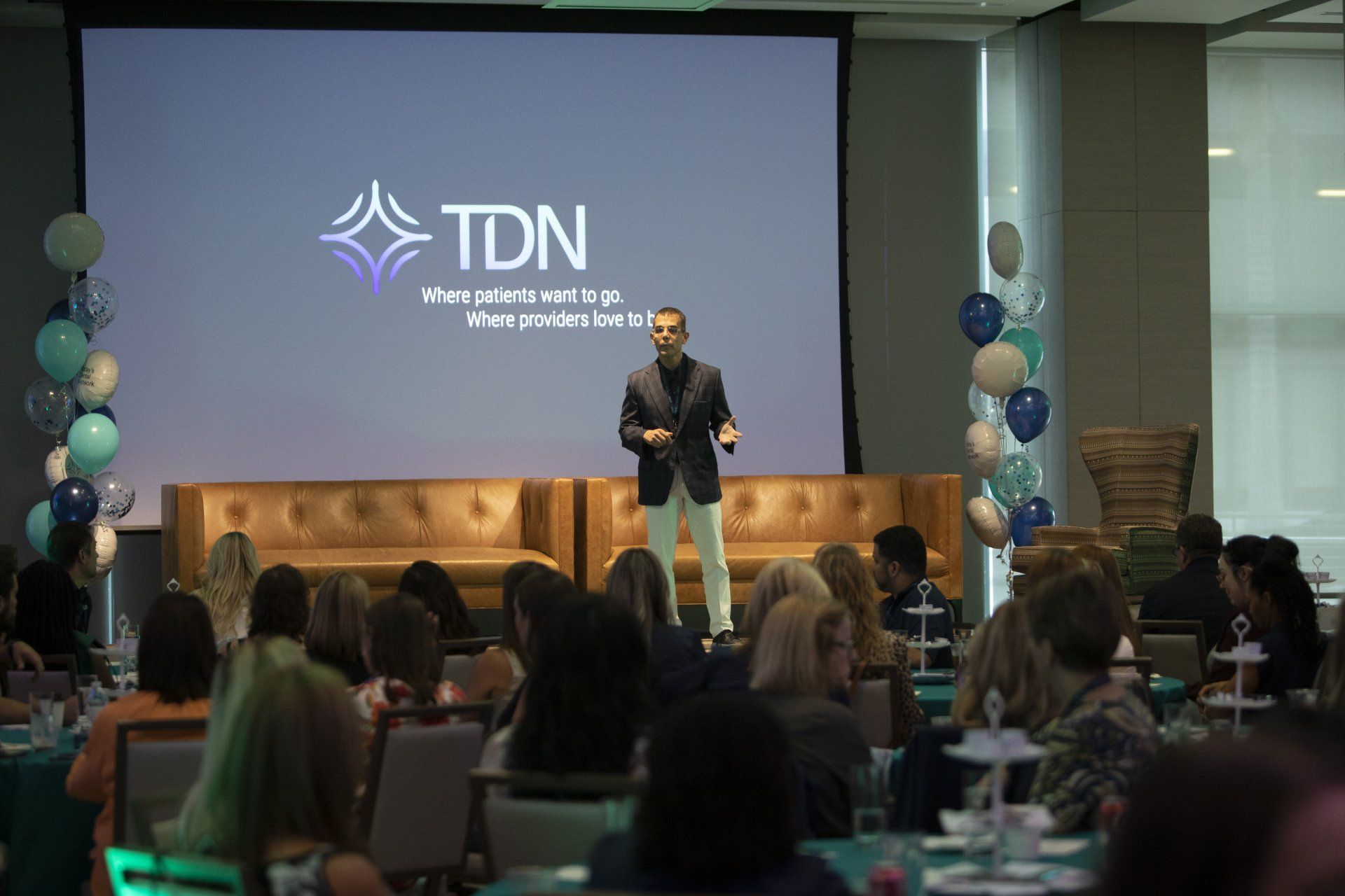 A man is giving a presentation to a group of people in front of a large screen.