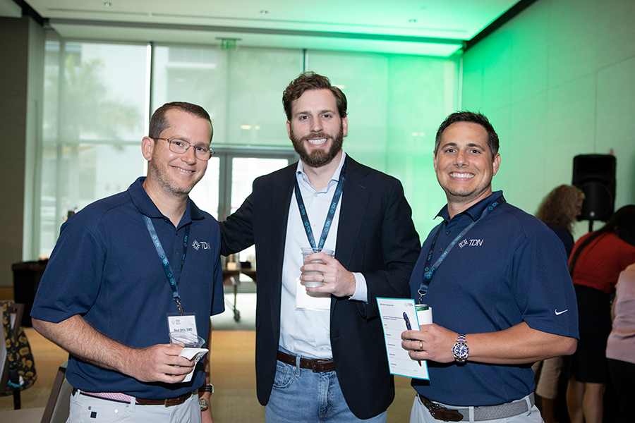 Three men are posing for a picture in a room with green lights.
