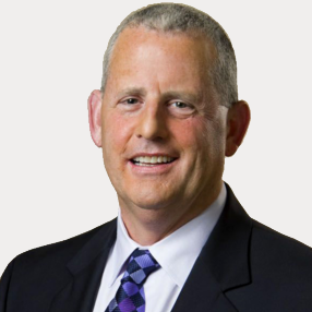 A man in a suit and tie is smiling for the camera