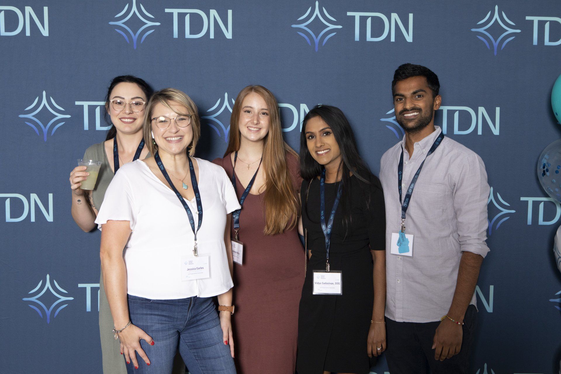 A group of people are posing for a picture in front of a wall that says tdn.