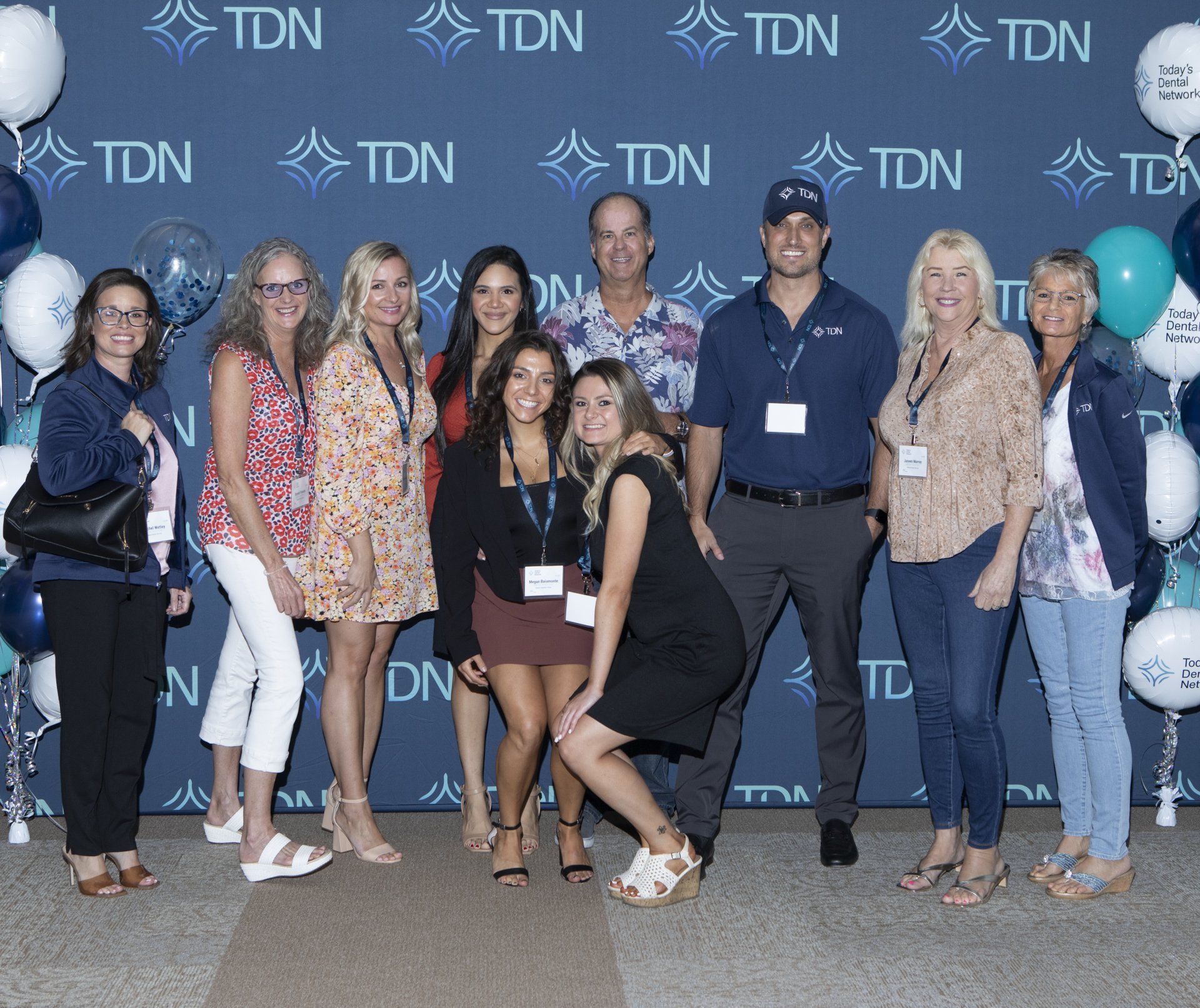 A group of people posing for a picture in front of a wall that says tdn