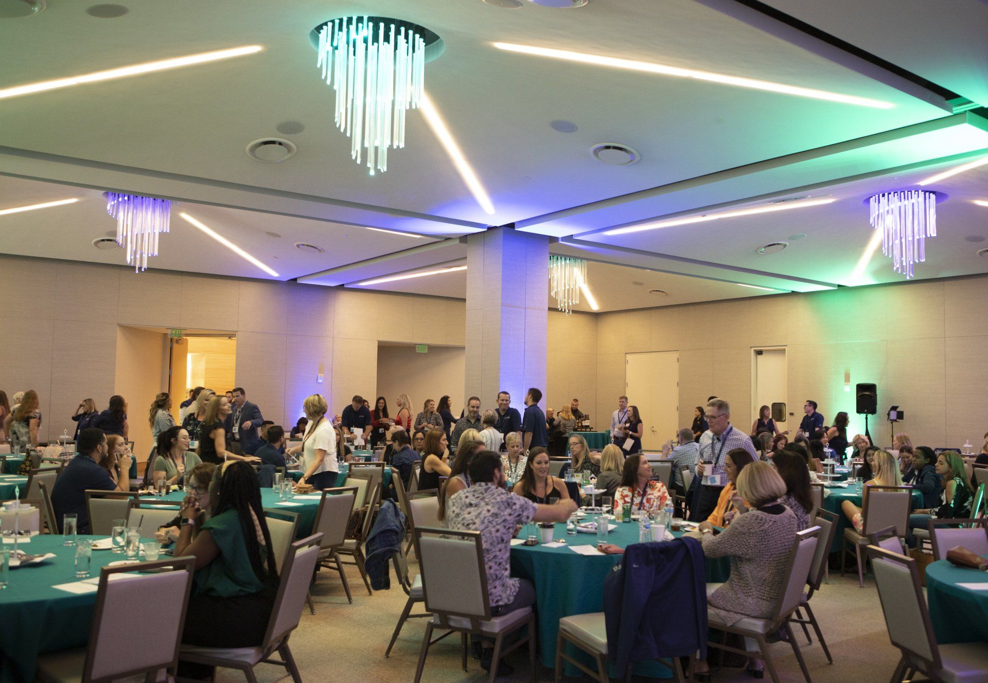 A large room filled with people sitting at tables and chairs.