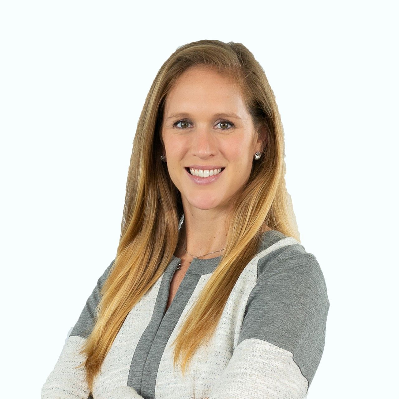 A woman with long blonde hair is wearing a grey and white sweater and smiling.