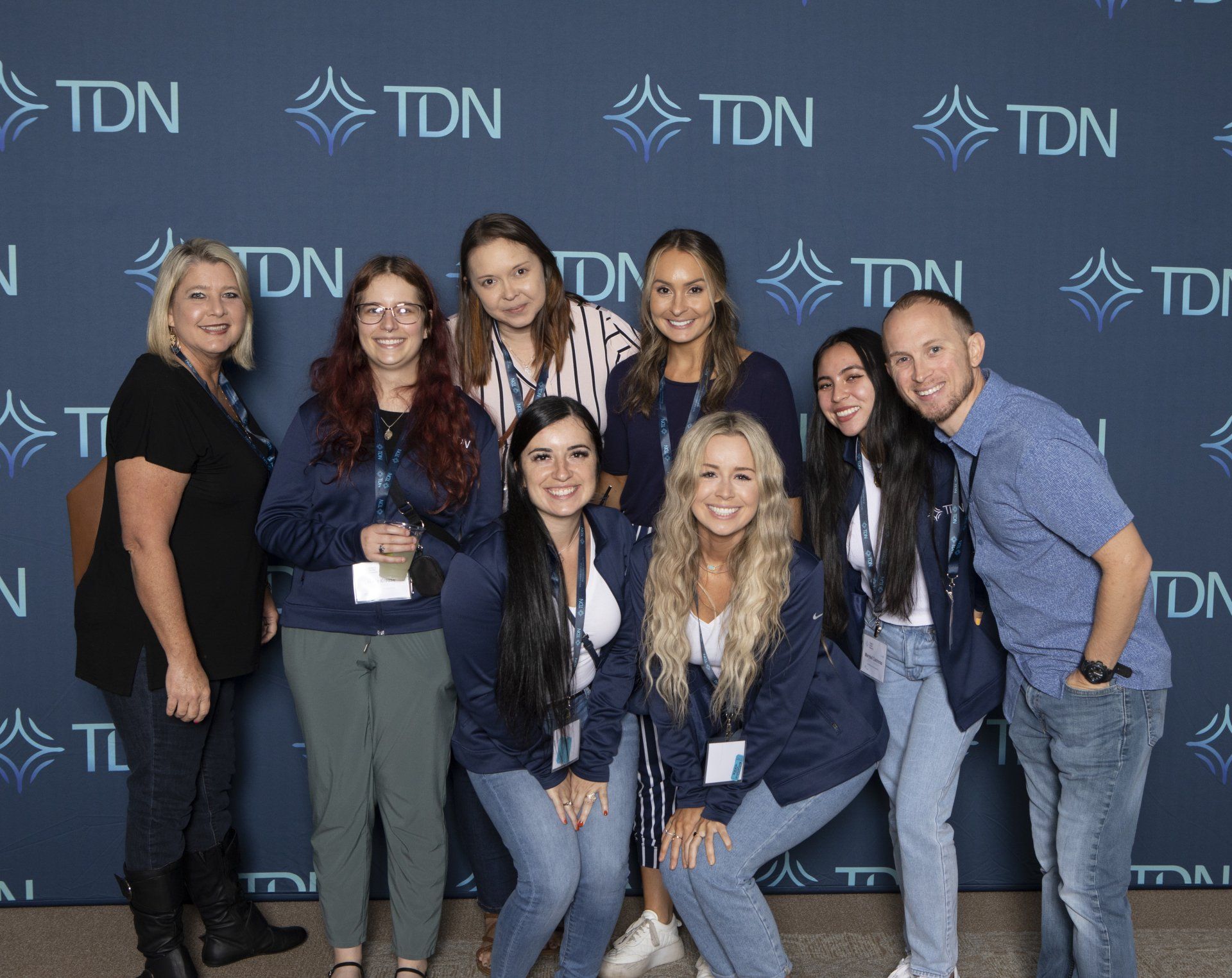 A group of people are posing for a picture in front of a blue wall.