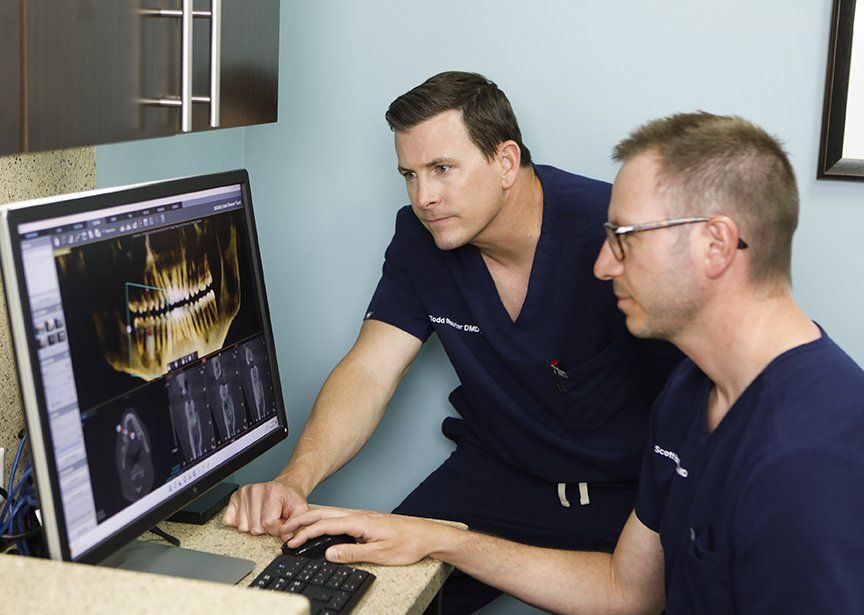 Two men in scrubs are looking at a computer screen