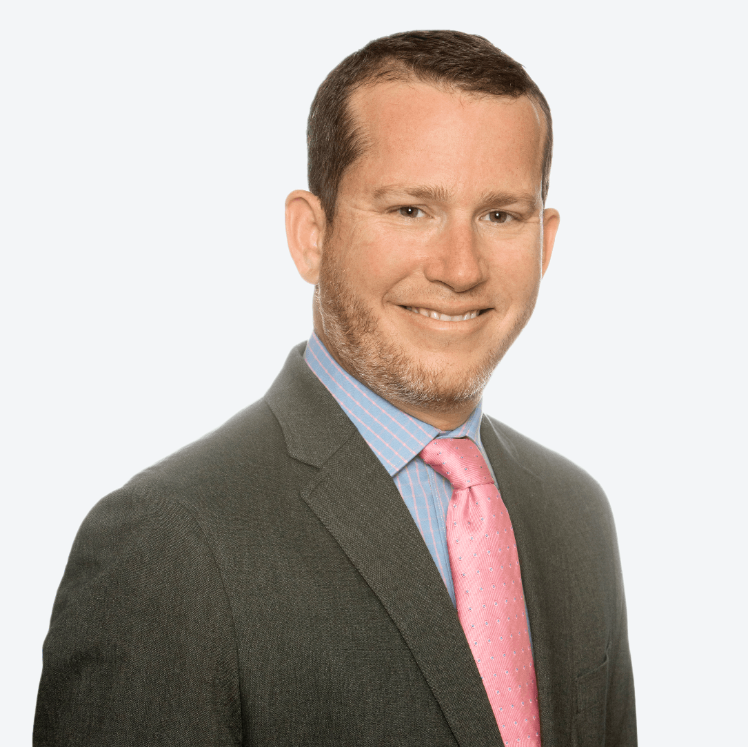 A man in a suit and pink tie is smiling for the camera.