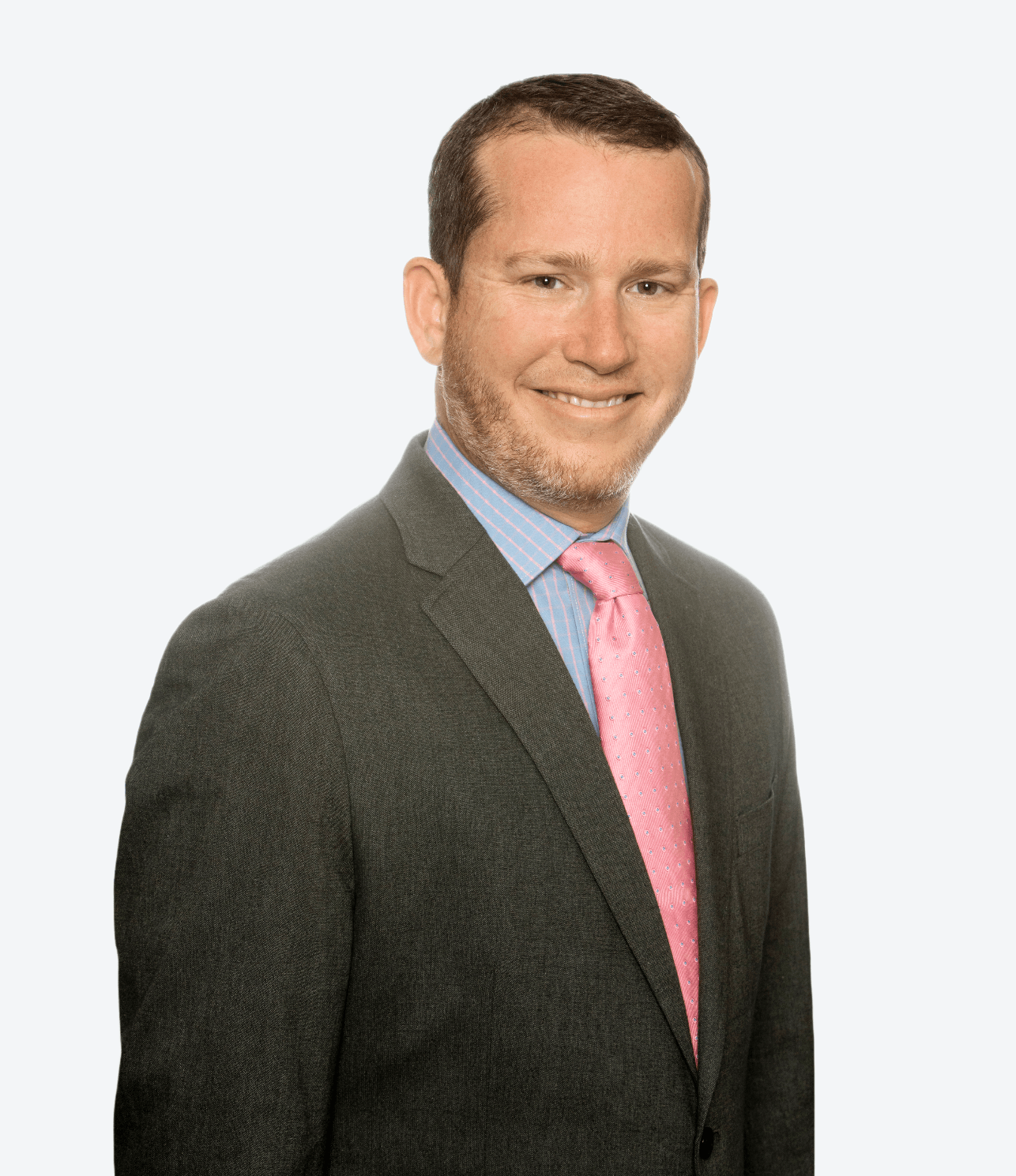 A man in a suit and pink tie is smiling for the camera.