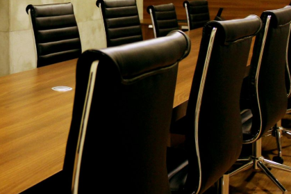 Black leather office chairs around a long wooden conference table.