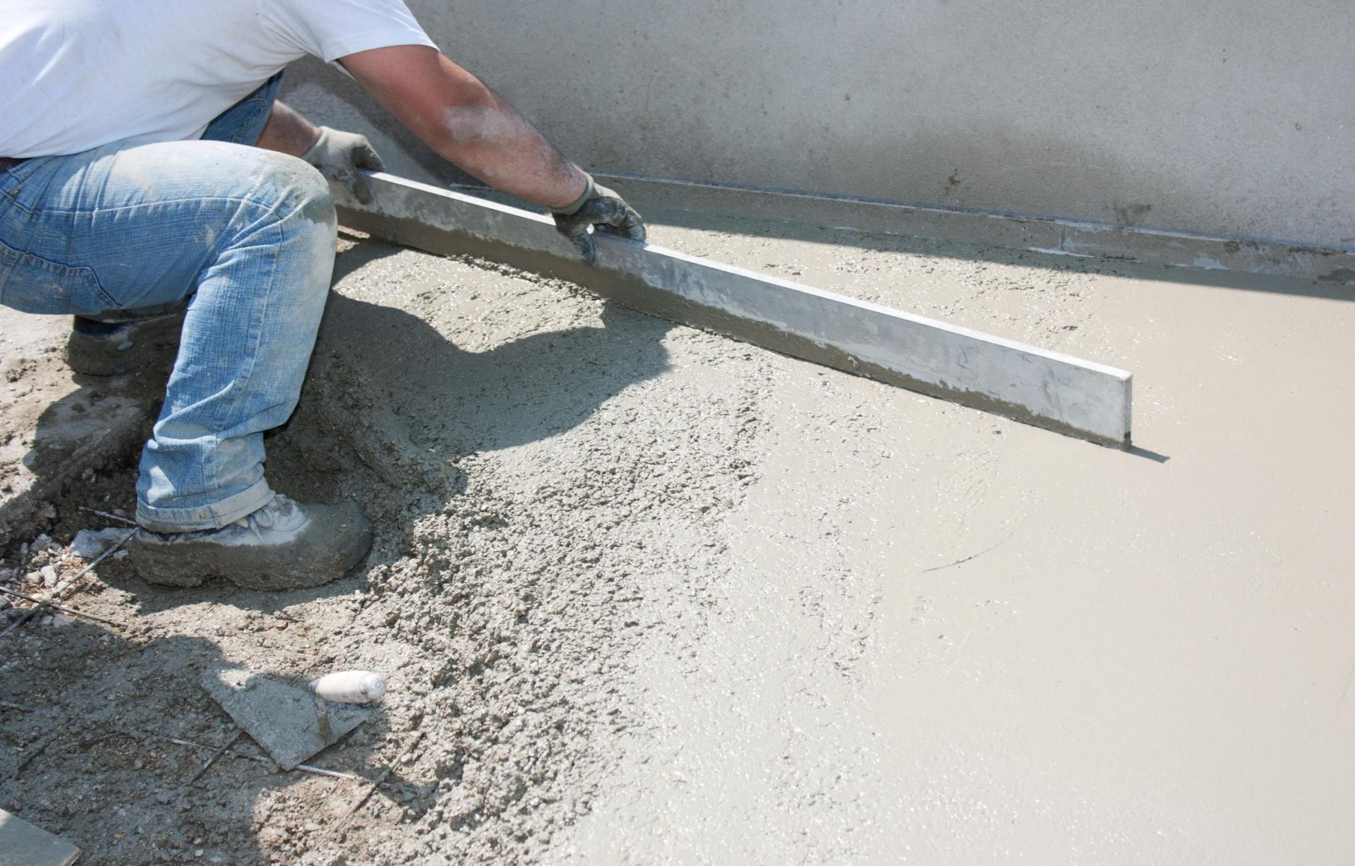 A man is leveling a concrete floor with a level
