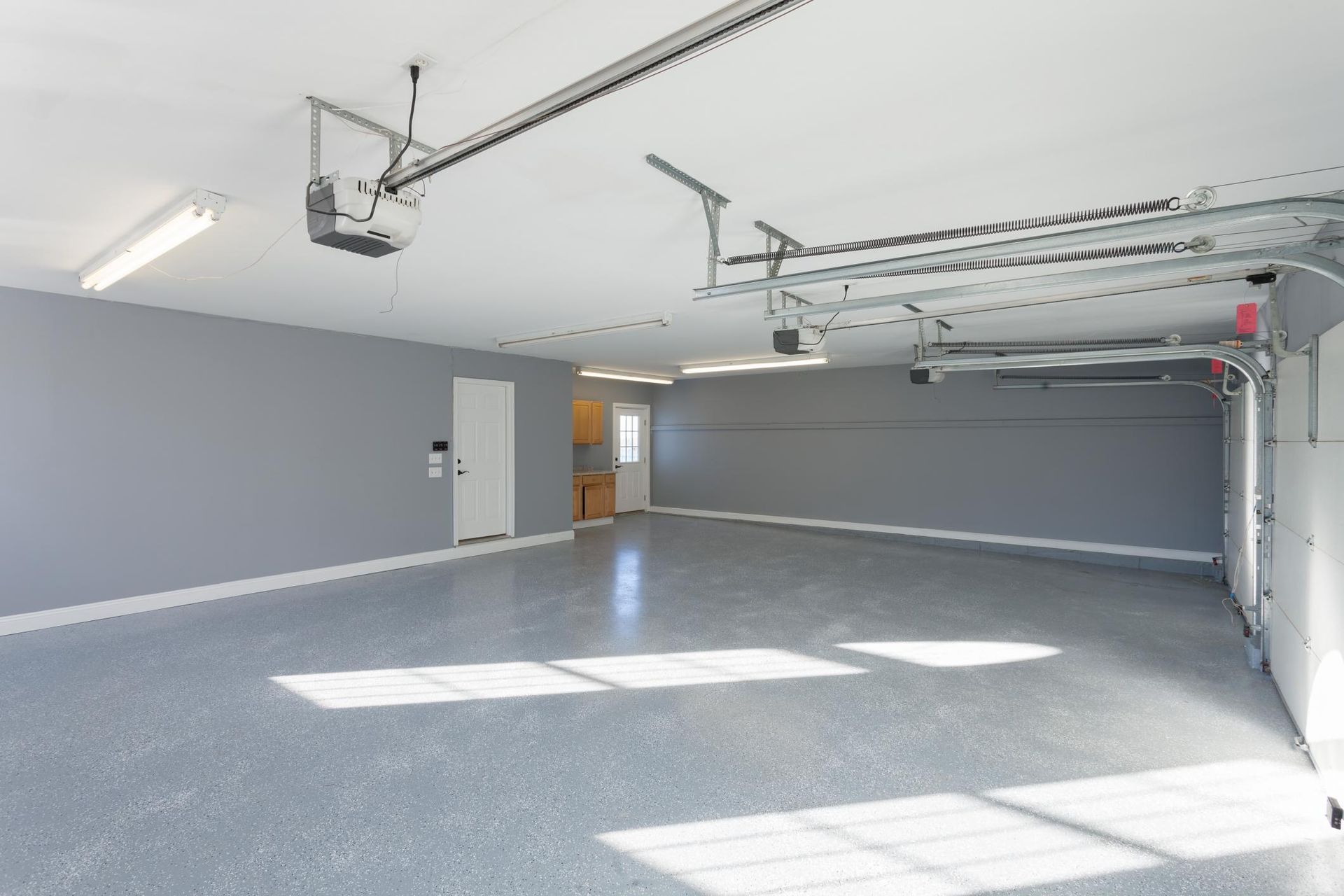 An empty garage with a garage door open and a ceiling lift