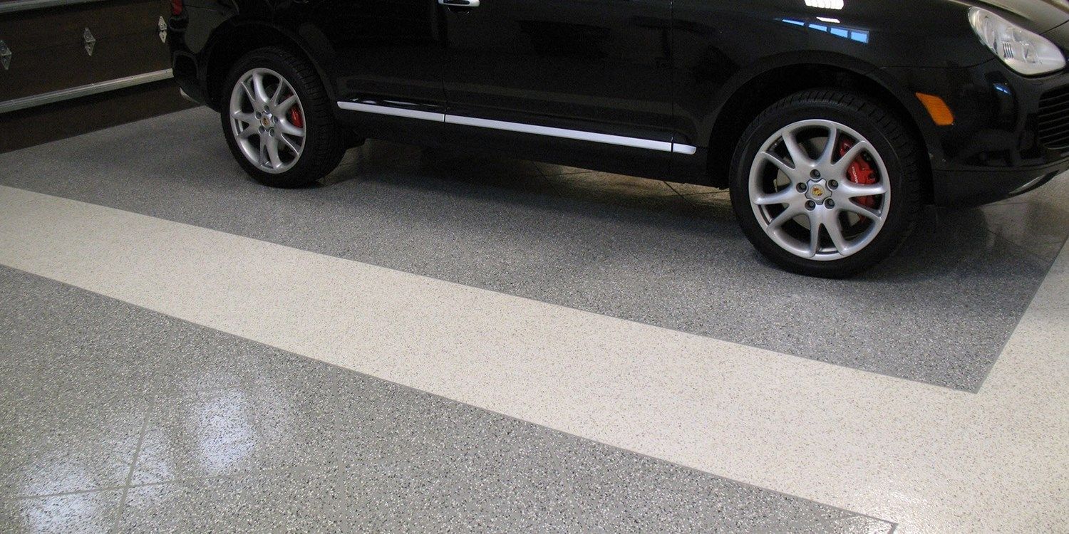 A black car is parked in a garage with a white stripe on the floor