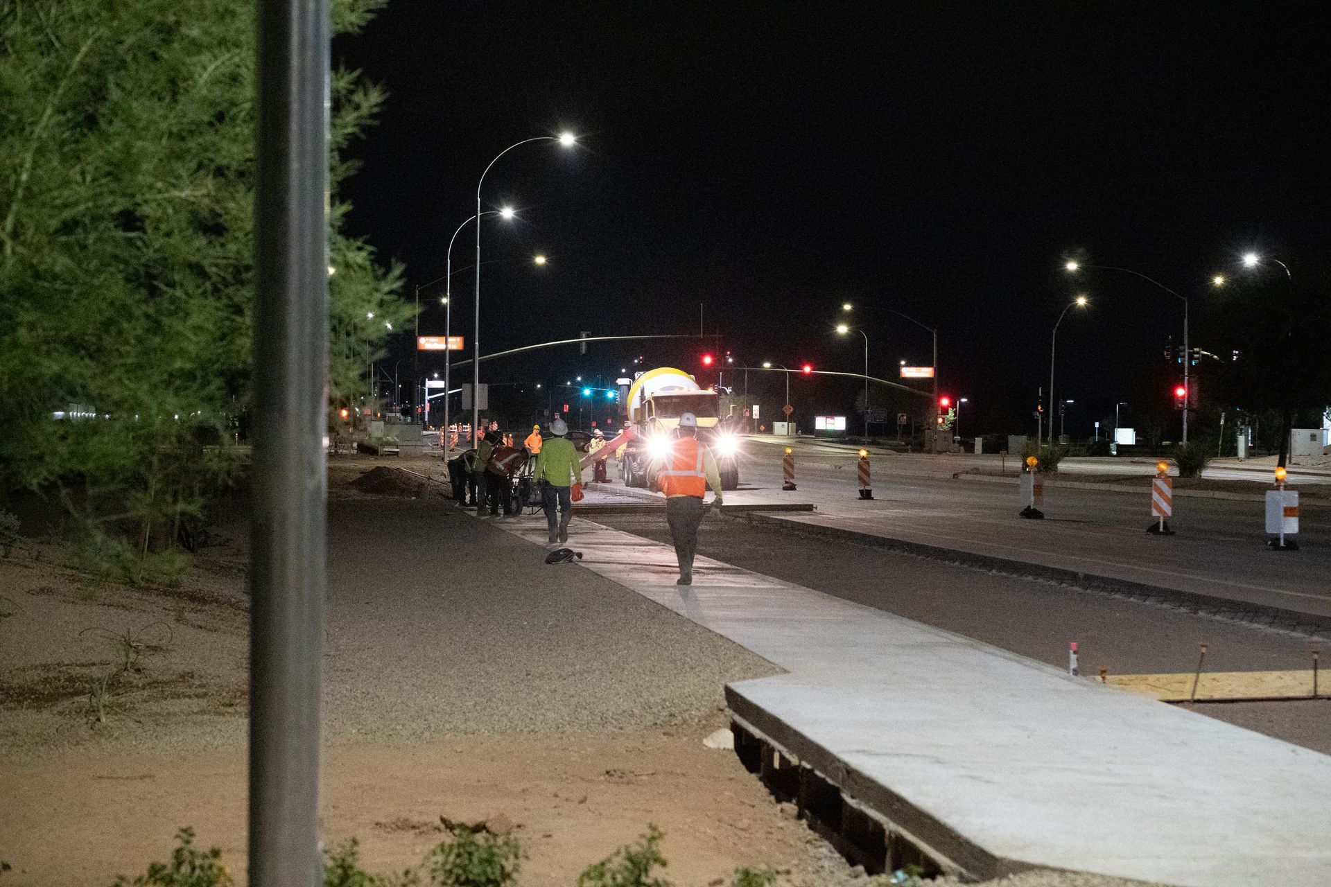 Construction workers paving a road at night. Streetlights illuminate the scene.