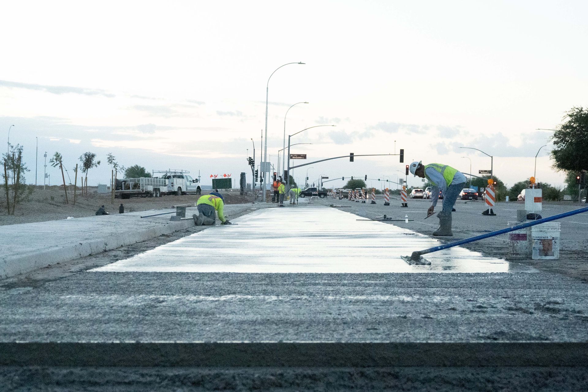 Construction workers smoothing wet concrete on a road.