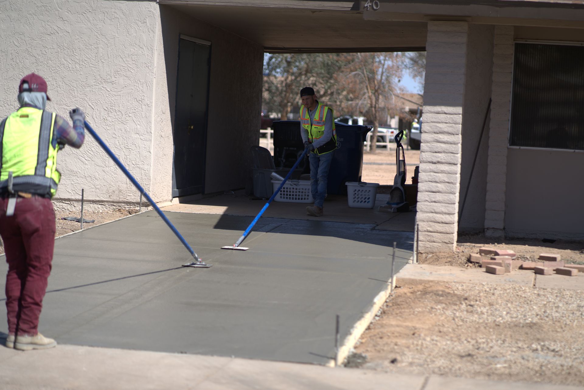 A concrete walkway leading to a house with a lush green lawn.