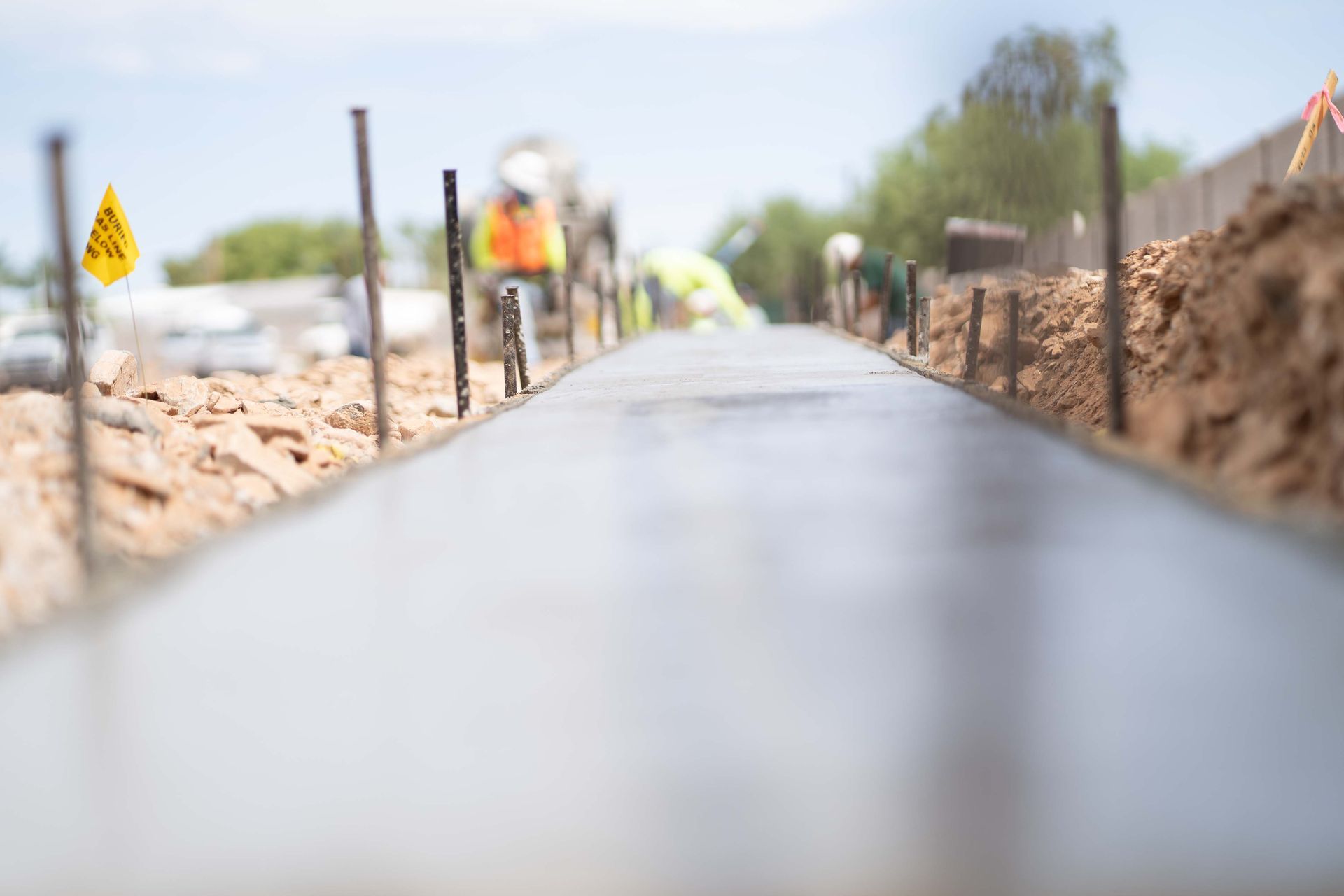 A concrete walkway leading to a house with a lush green lawn.