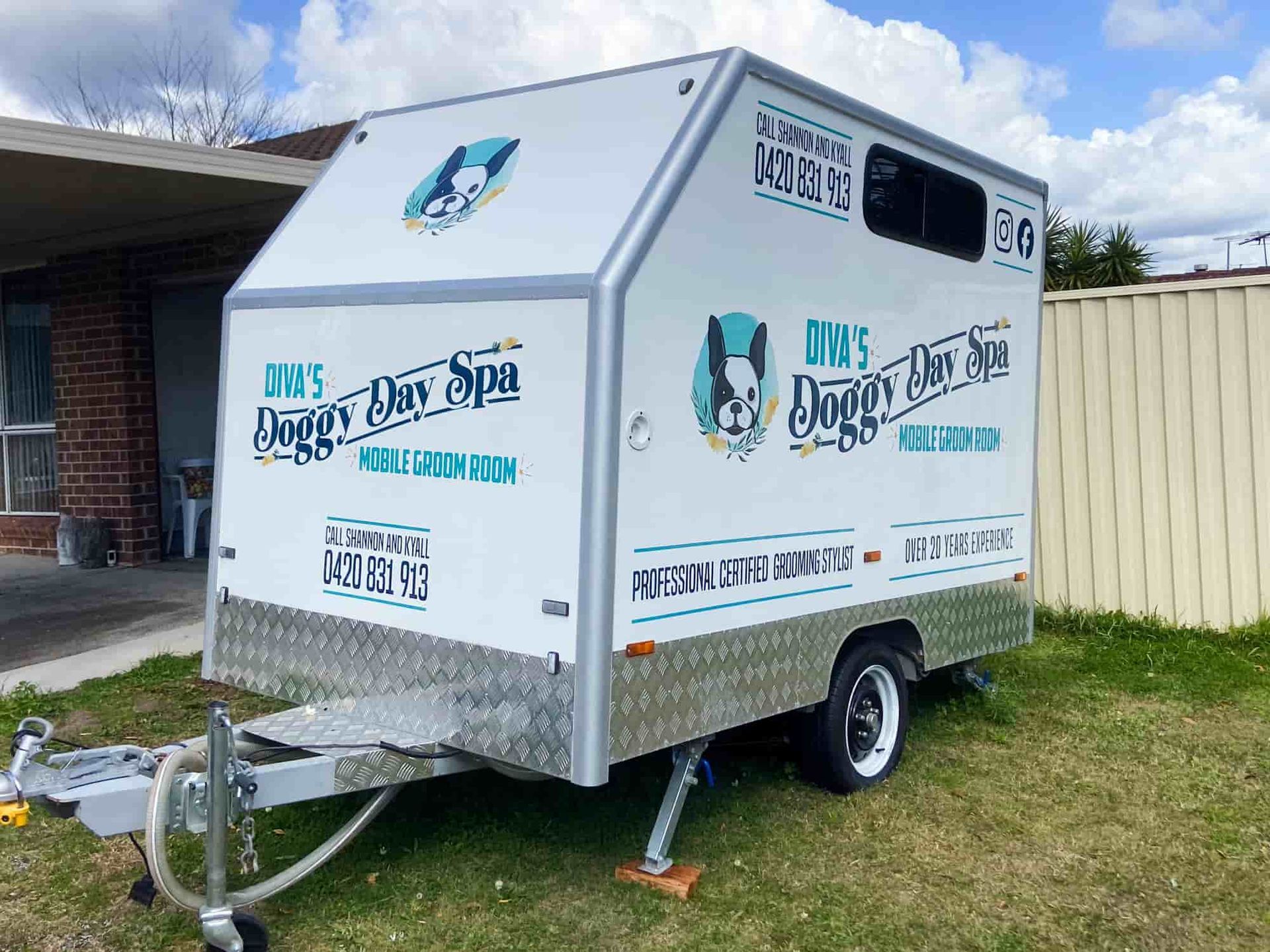A White Trailer Is Parked In The Grass In Front Of A House — Solis Signs in Toukley, NSW