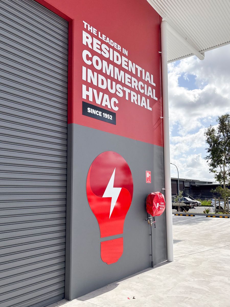 A Red Garage Door Is On The Side Of A Building — Solis Signs in Toukley, NSW