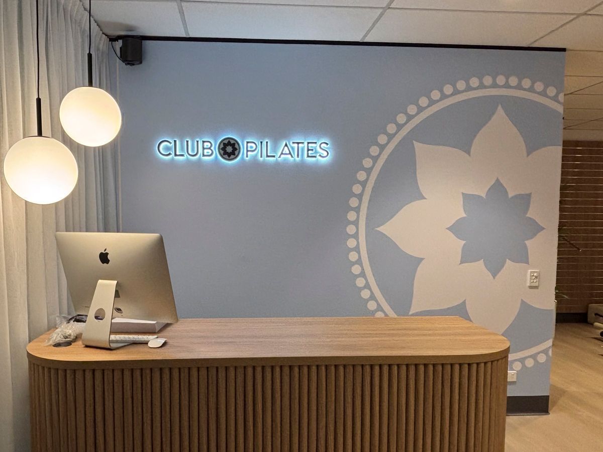 Reception desk of a pilates club with adhesive on the back wall — Solis Signs in Toukley, NSW