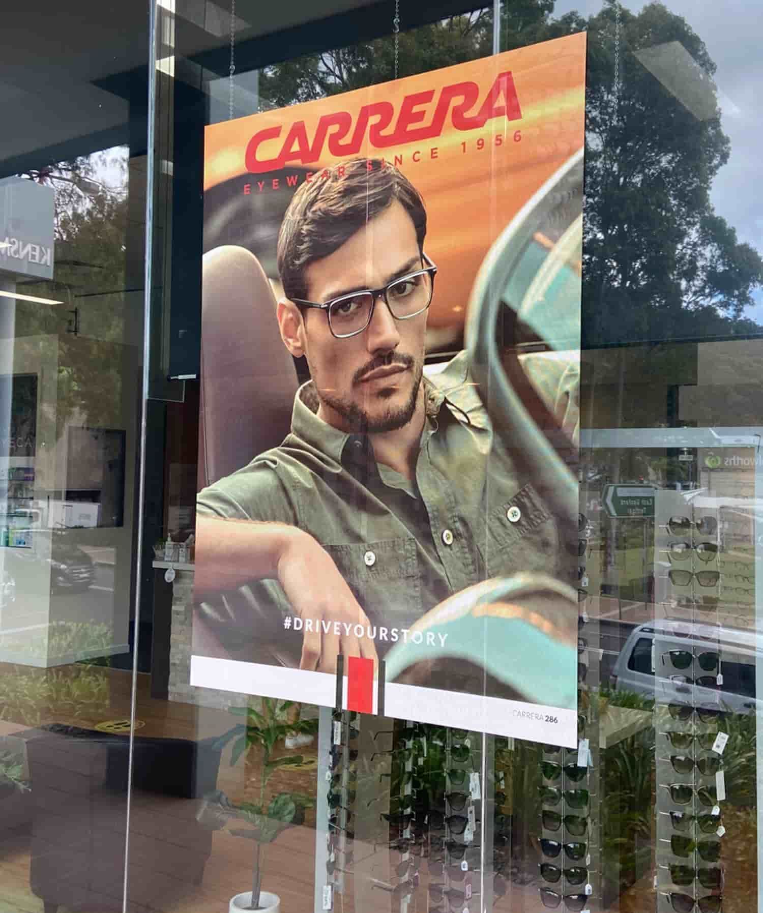 A man wearing glasses is driving a car on a carrera poster — Solis Signs in Toukley, NSW