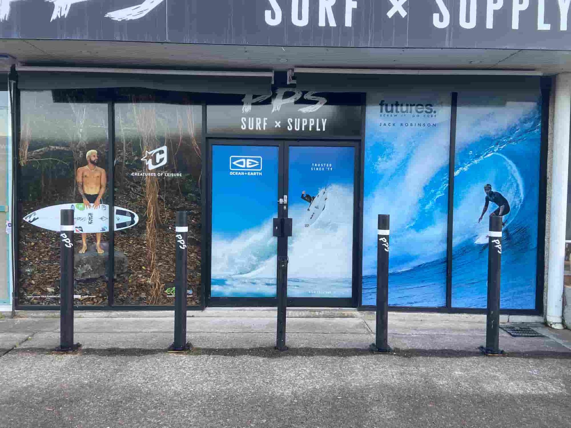 A Store Front With A Picture Of A Man Riding A Wave On A Surfboard — Solis Signs in Toukley, NSW