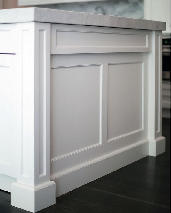 A kitchen island with white cabinets and a marble counter top