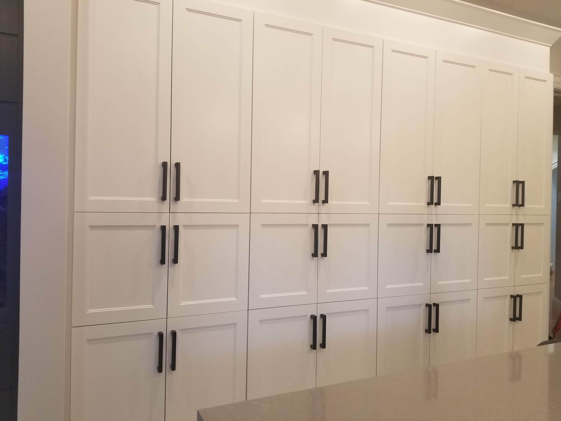 A kitchen with a lot of white cabinets and black handles