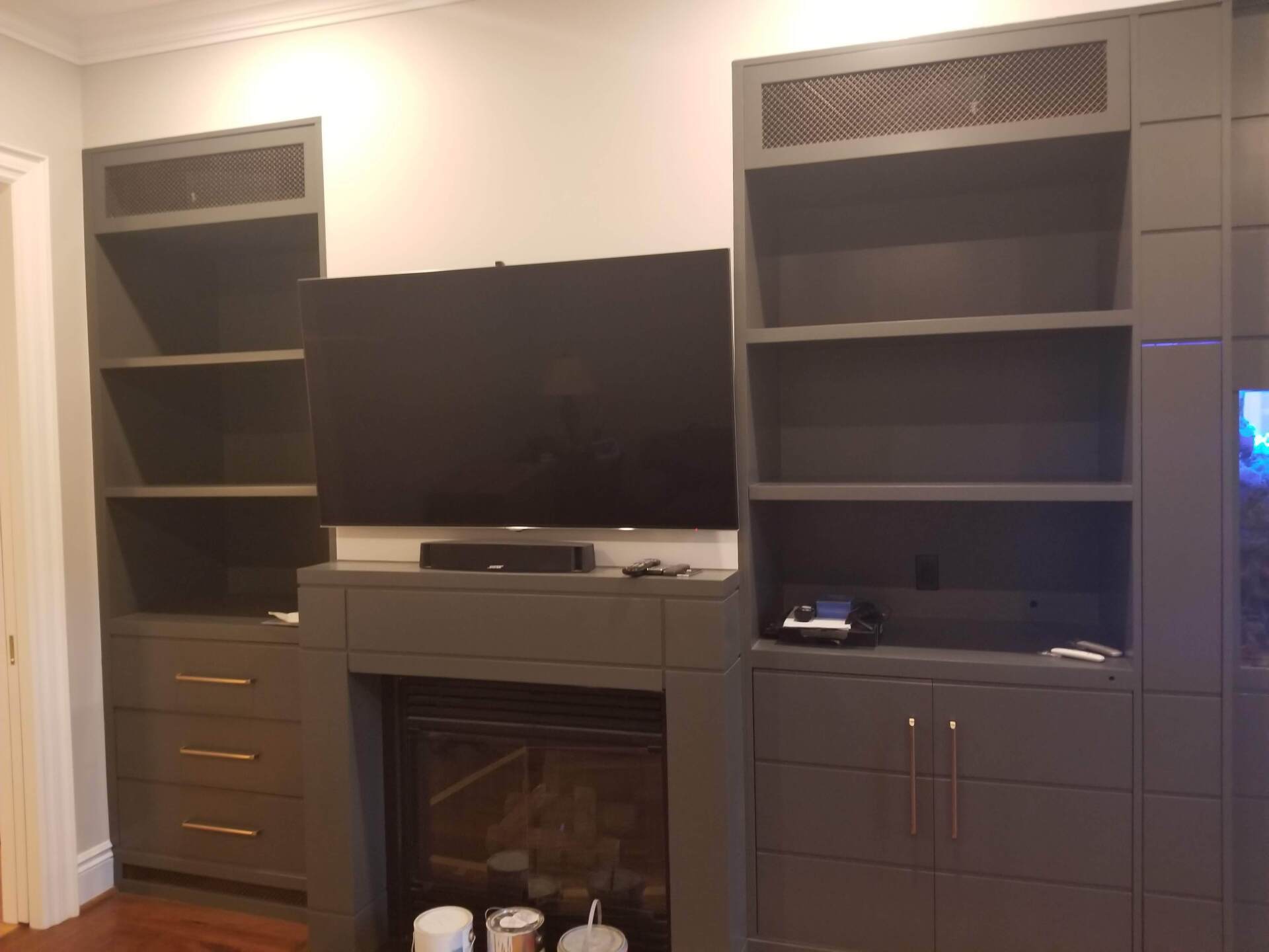 A living room with a fireplace , shelves , and a flat screen tv.