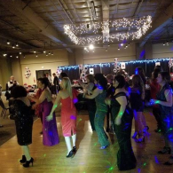 People dancing in a dimly lit ballroom with blue and purple lights