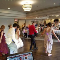Guests dancing at a wedding reception in a banquet hall with chandeliers