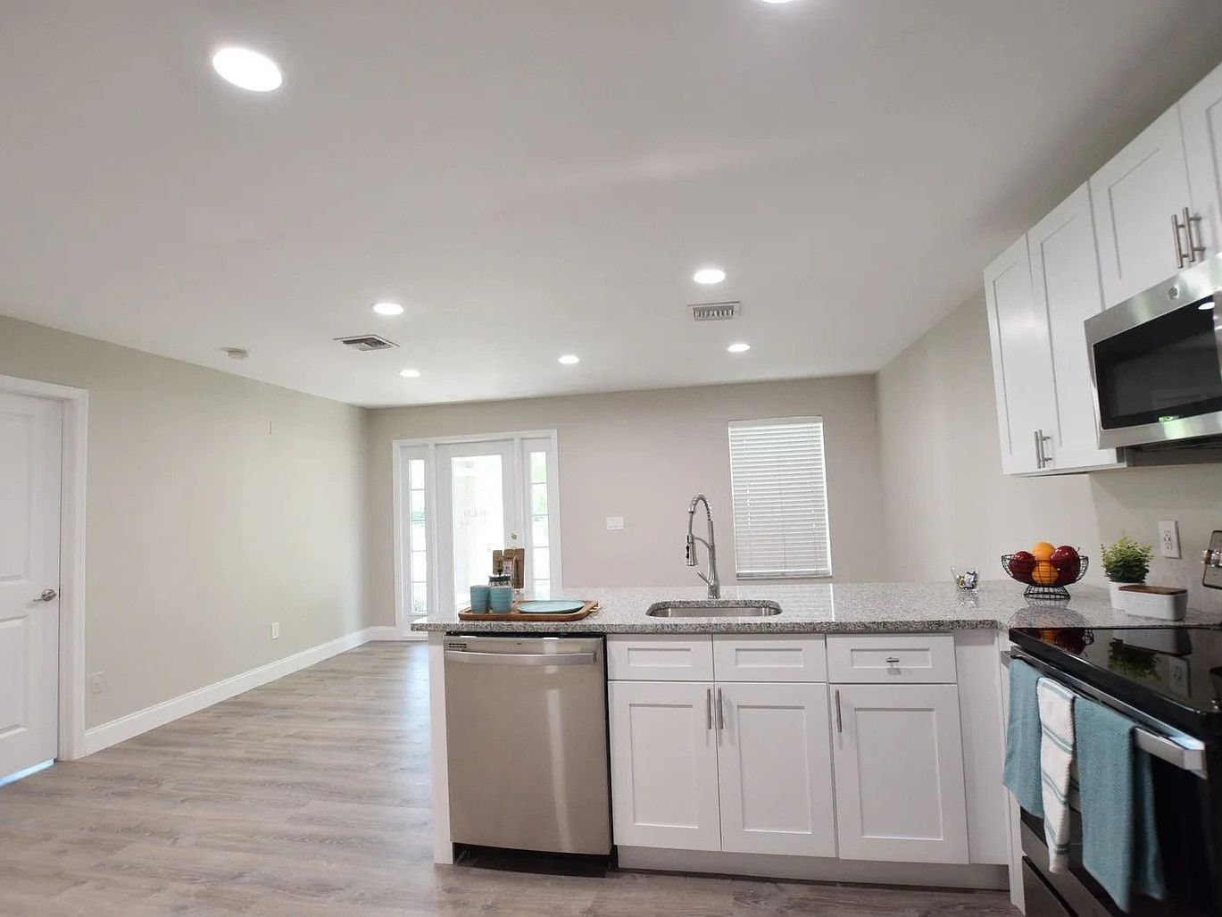 A kitchen with white cabinets , stainless steel appliances , a sink , and a microwave.