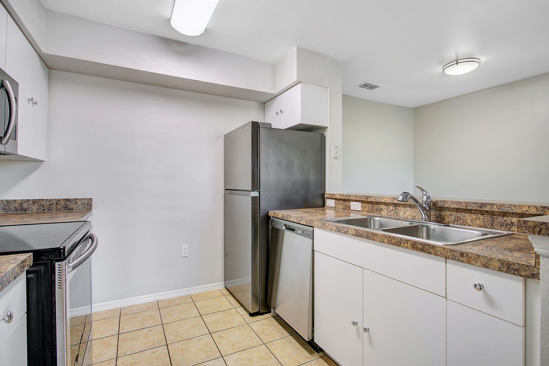 A kitchen with a refrigerator , sink , stove and microwave.