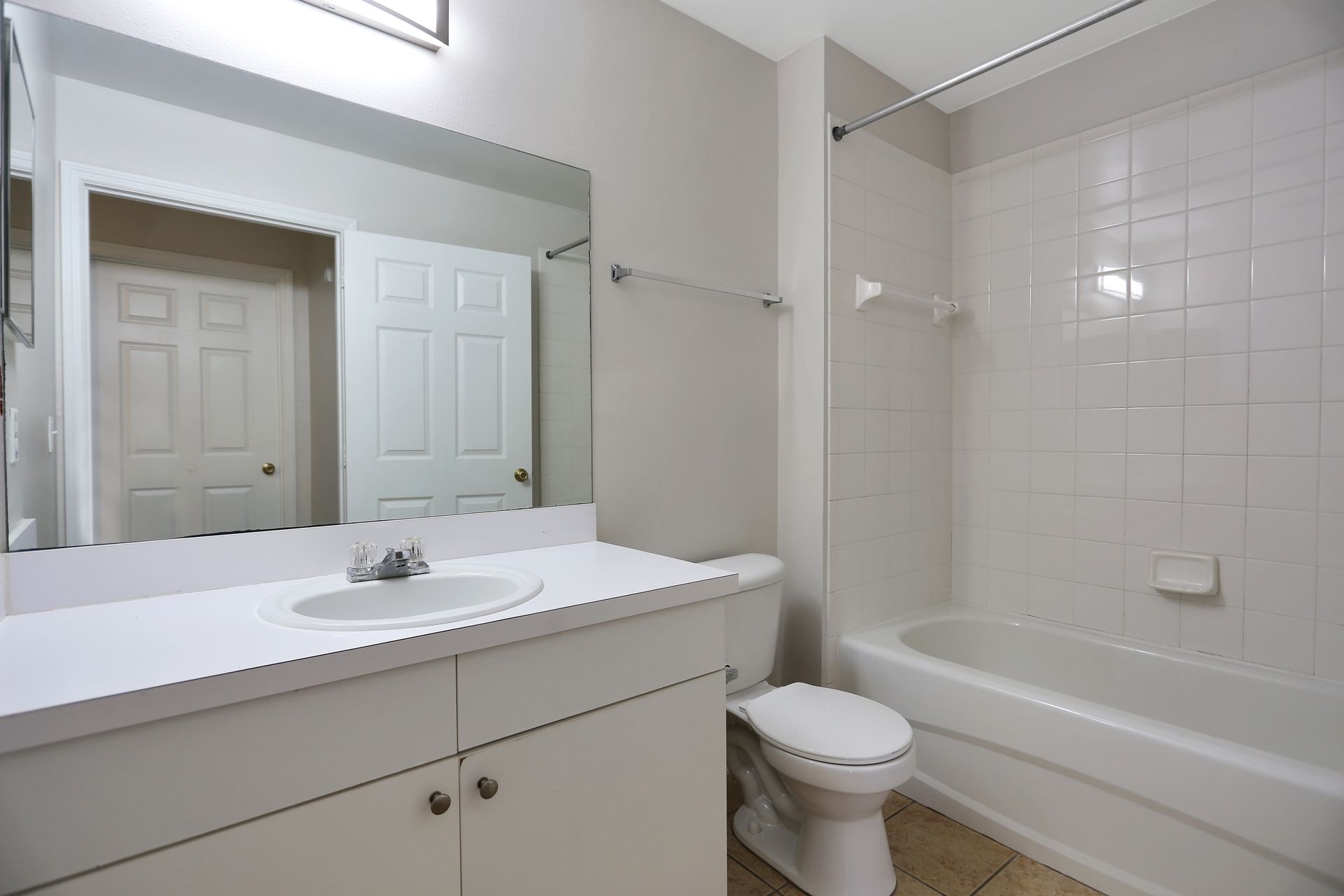 A bathroom with a sink , toilet , tub and mirror.