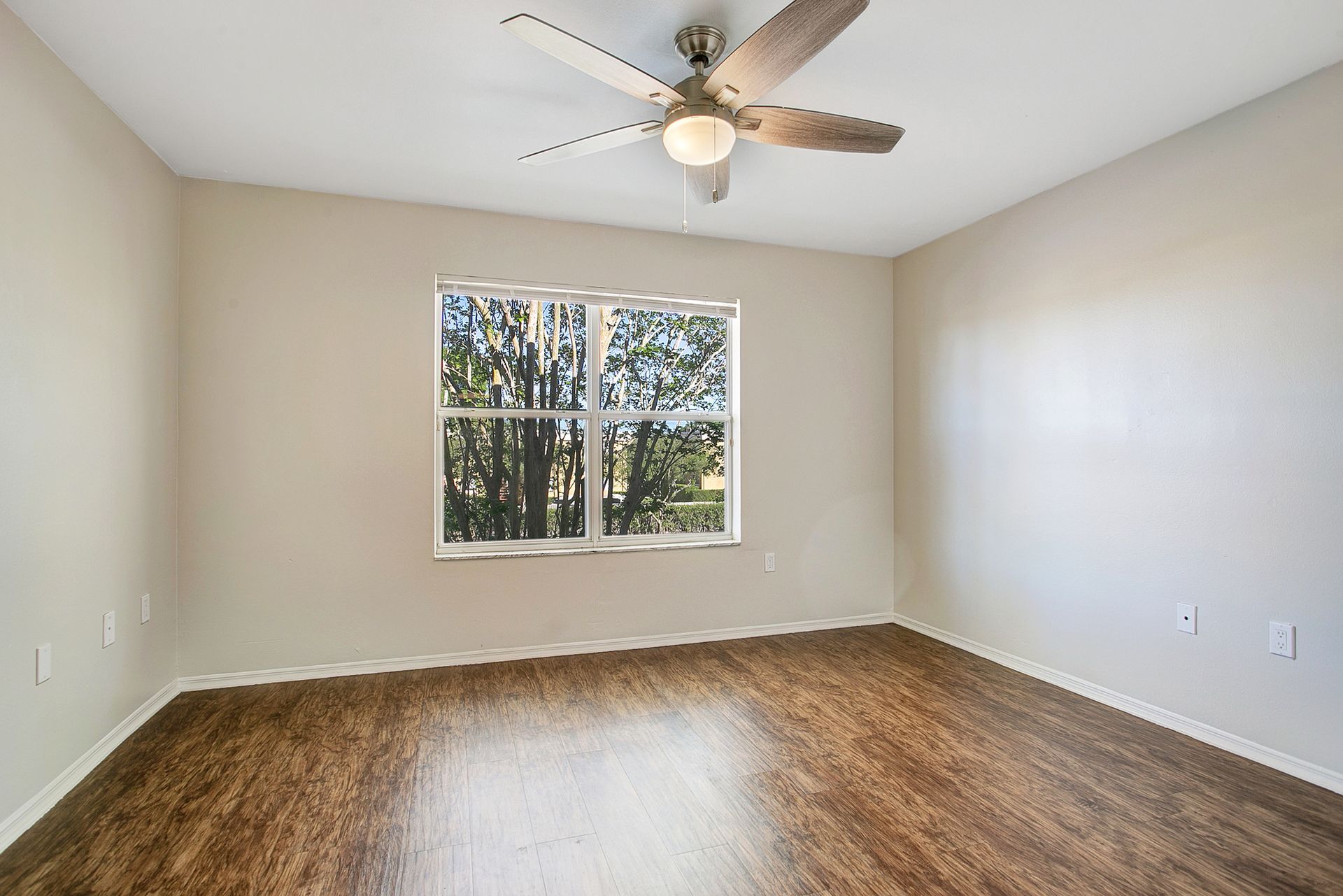 An empty room with a ceiling fan and a window.