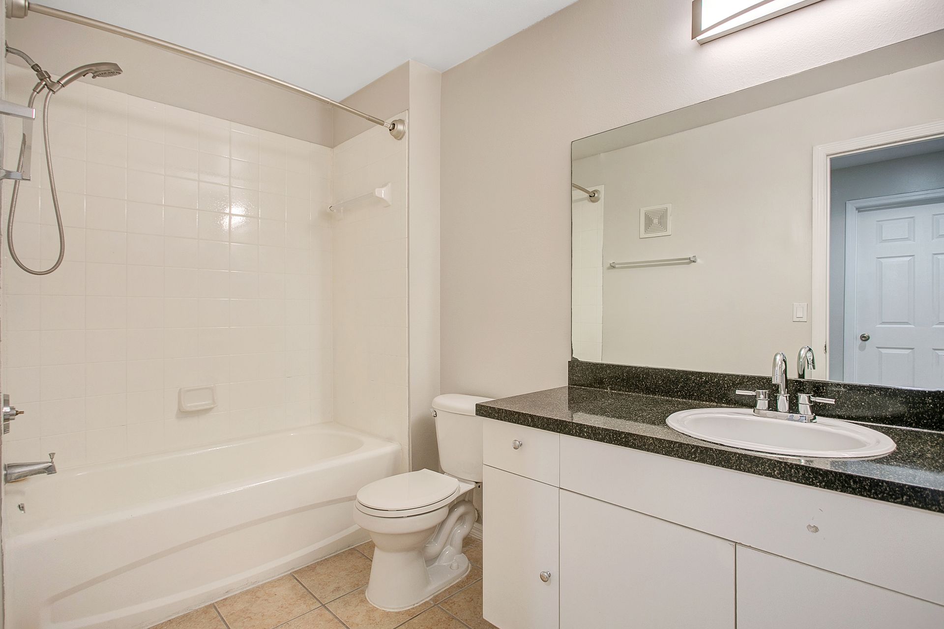 A bathroom with a tub , toilet , sink and mirror.