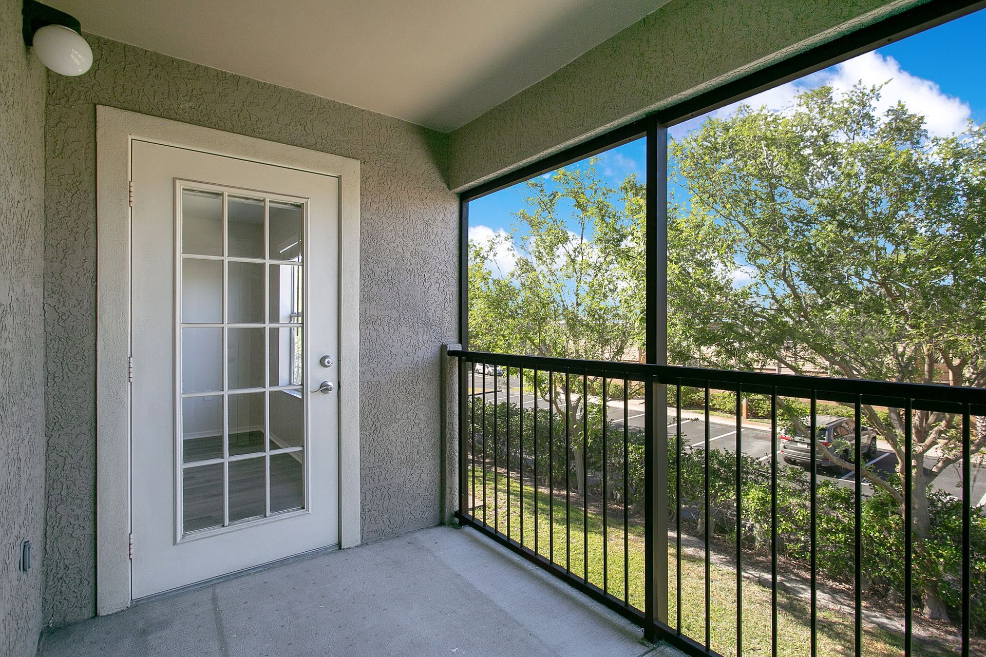 A screened in porch with a door and a railing.