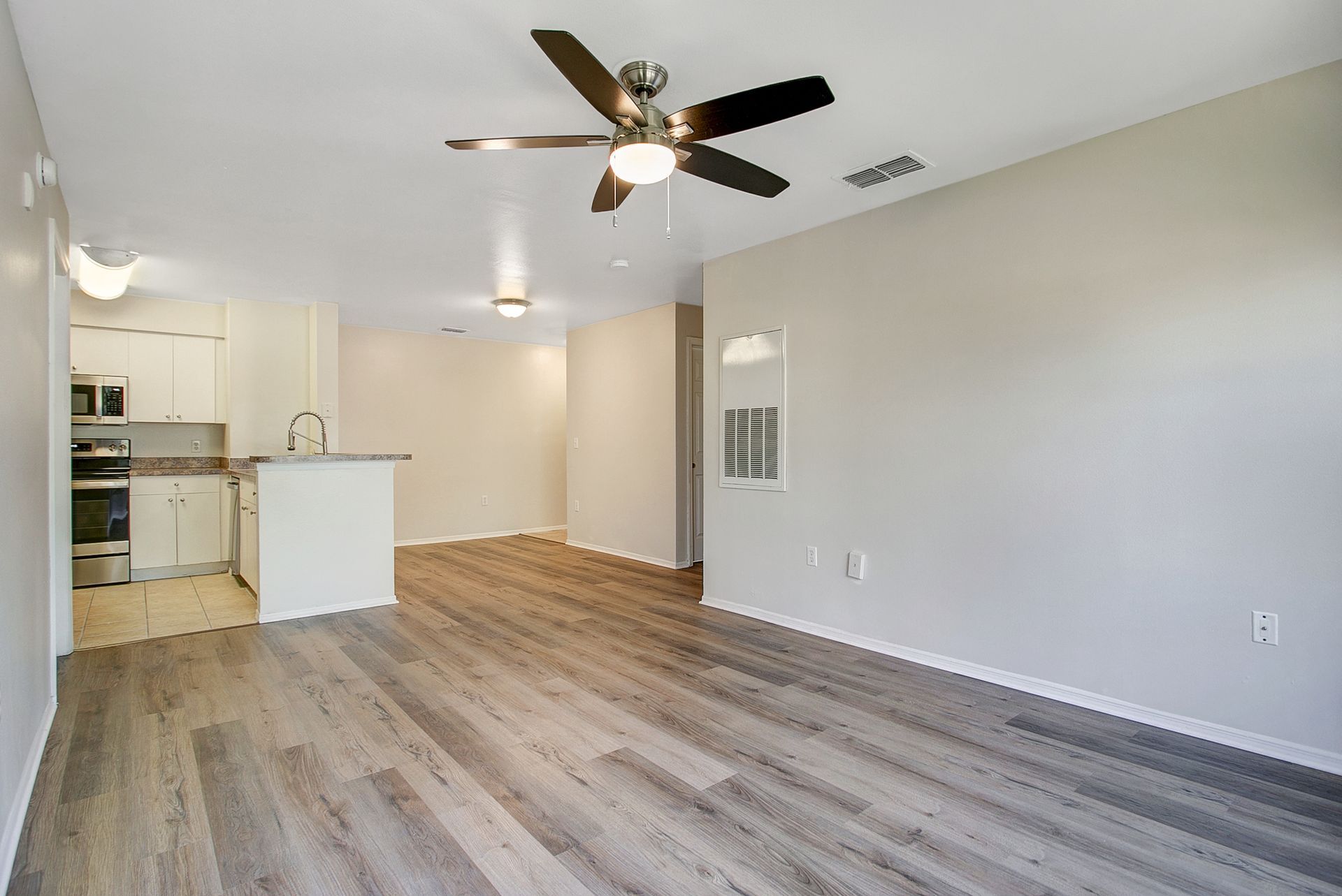 An empty living room with hardwood floors and a ceiling fan.