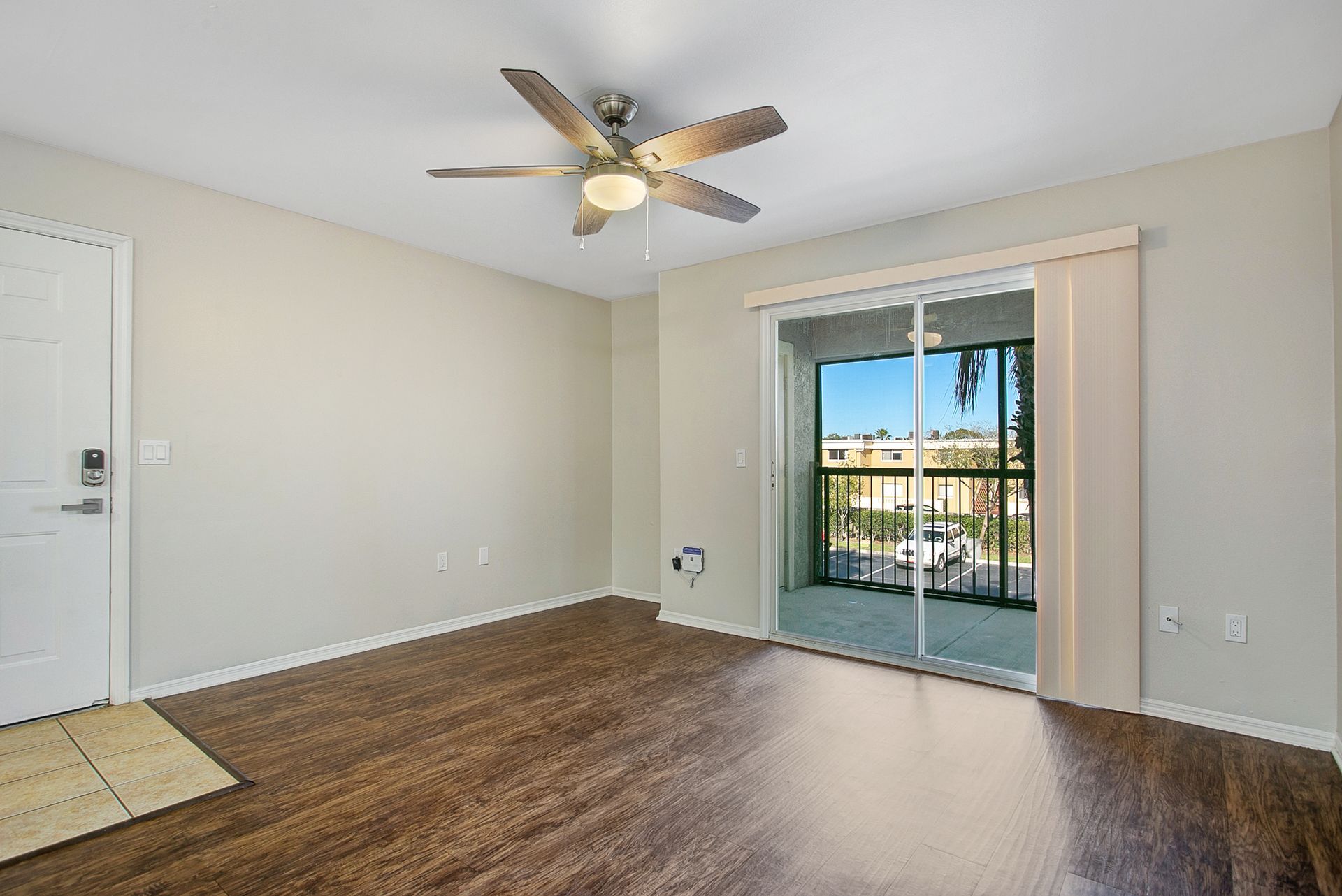 An empty living room with hardwood floors and a ceiling fan.