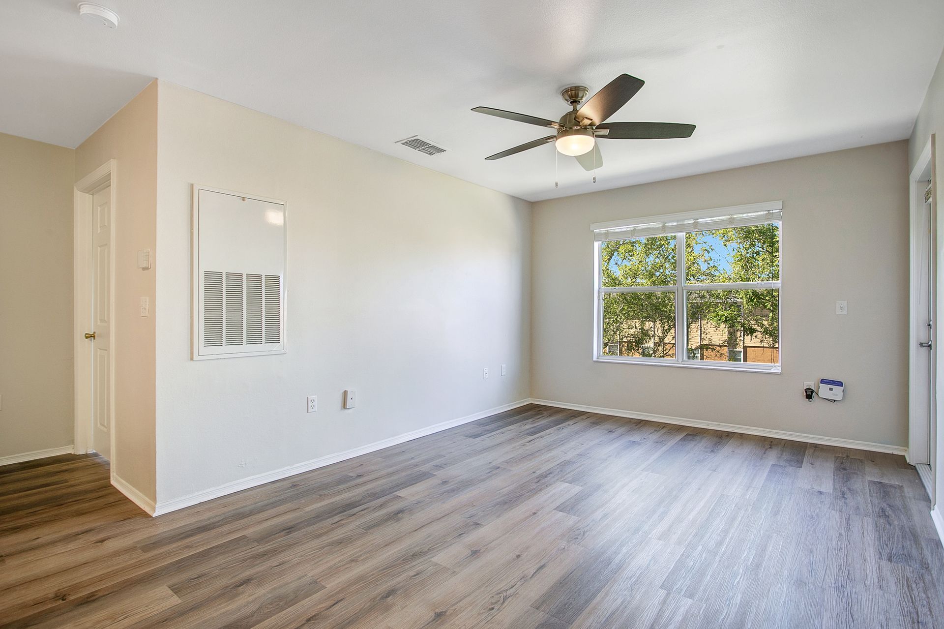 An empty living room with hardwood floors and a ceiling fan.