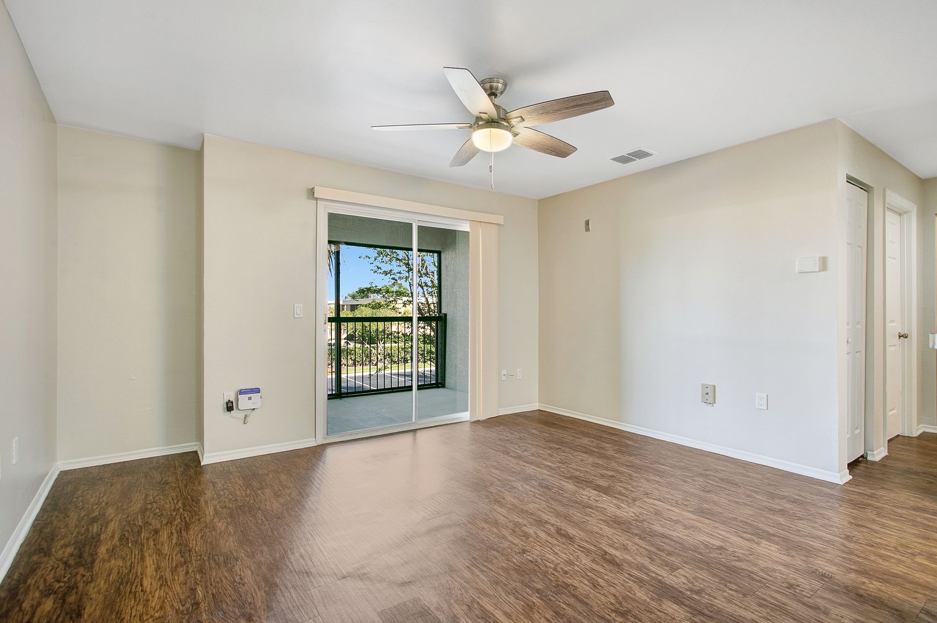 An empty living room with hardwood floors and a ceiling fan.
