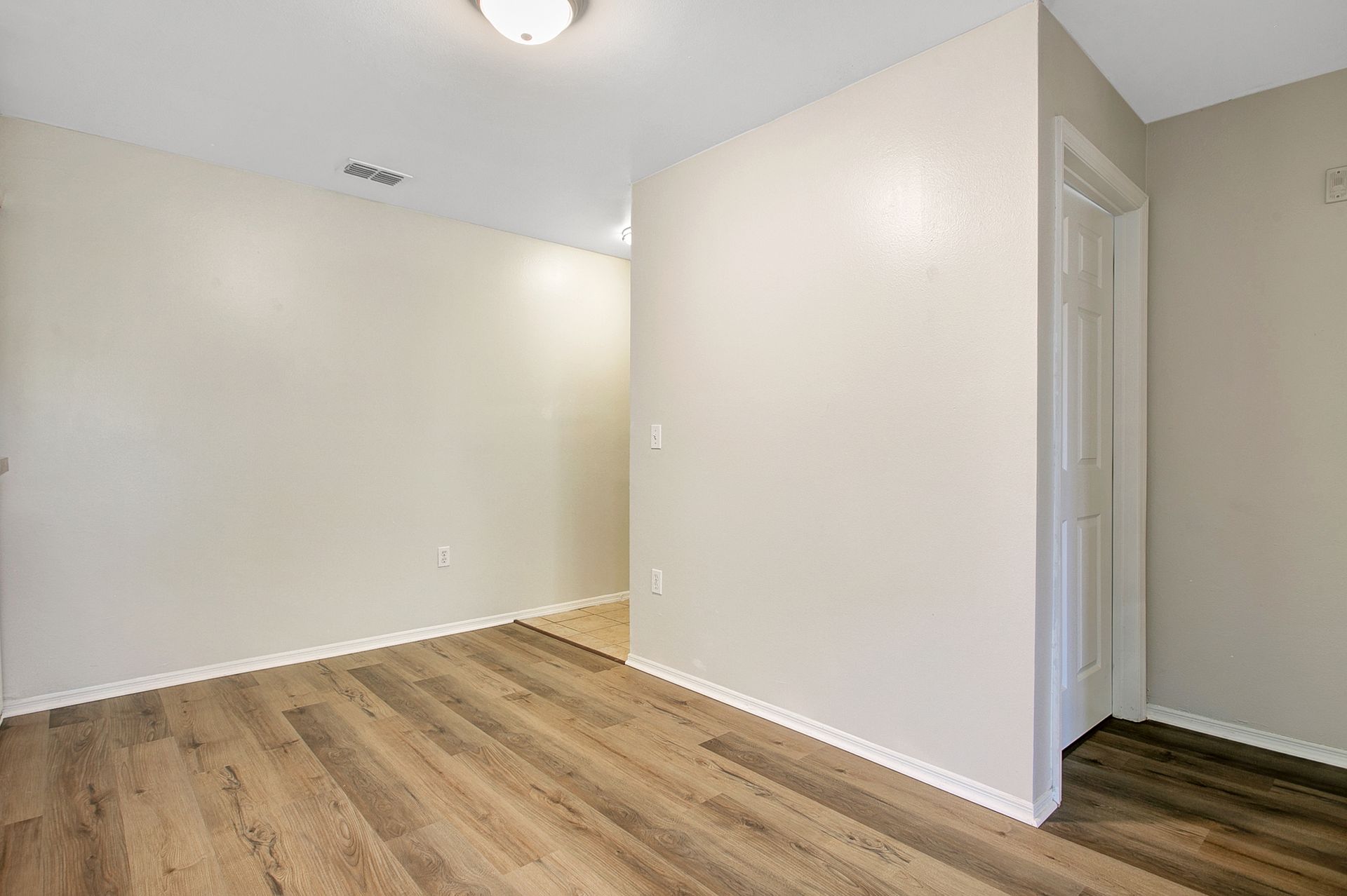 An empty room with hardwood floors and white walls.