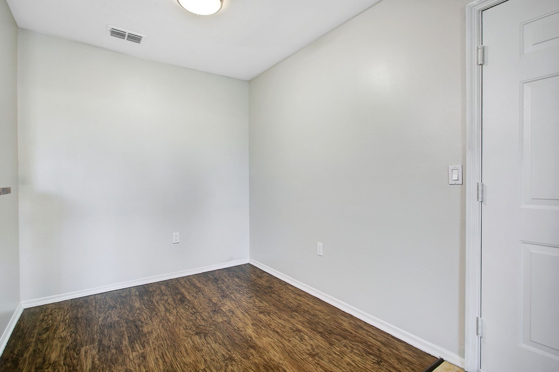 An empty room with hardwood floors and white walls.