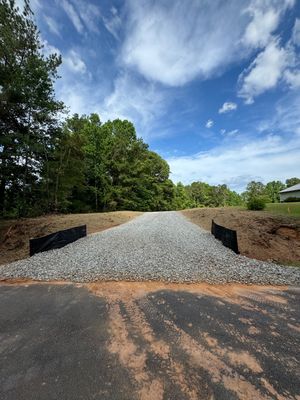 A gravel road with trees in the background and a blue sky