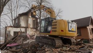 A cat excavator is demolishing a house.