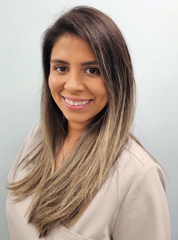 A woman with long brown hair is smiling for the camera.