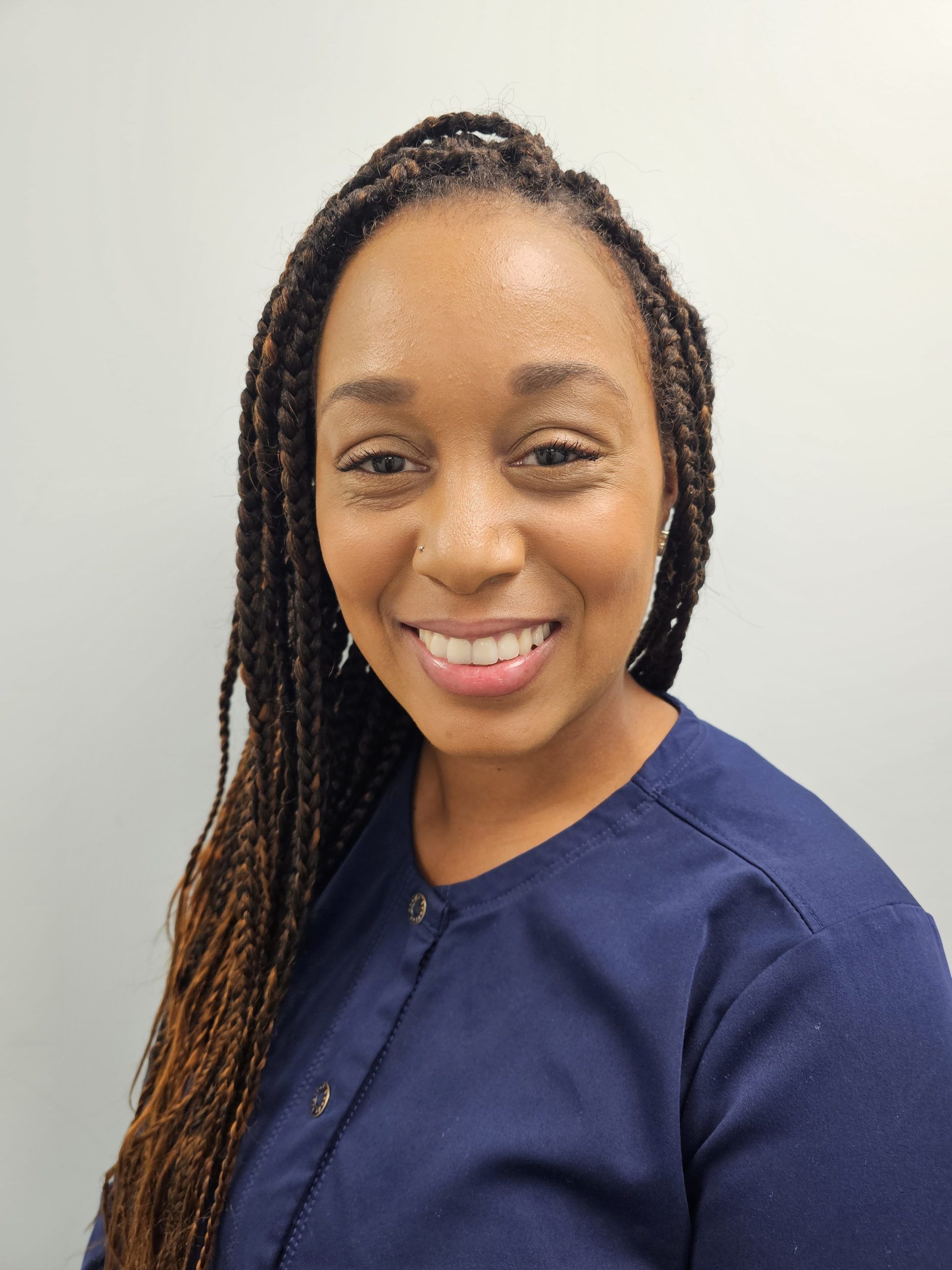 A woman with braids is smiling for the camera while wearing a blue shirt.