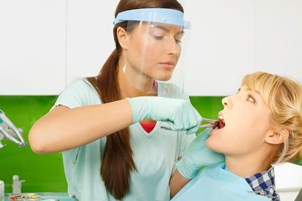A man is sitting in a dental chair getting his teeth examined by a dentist.