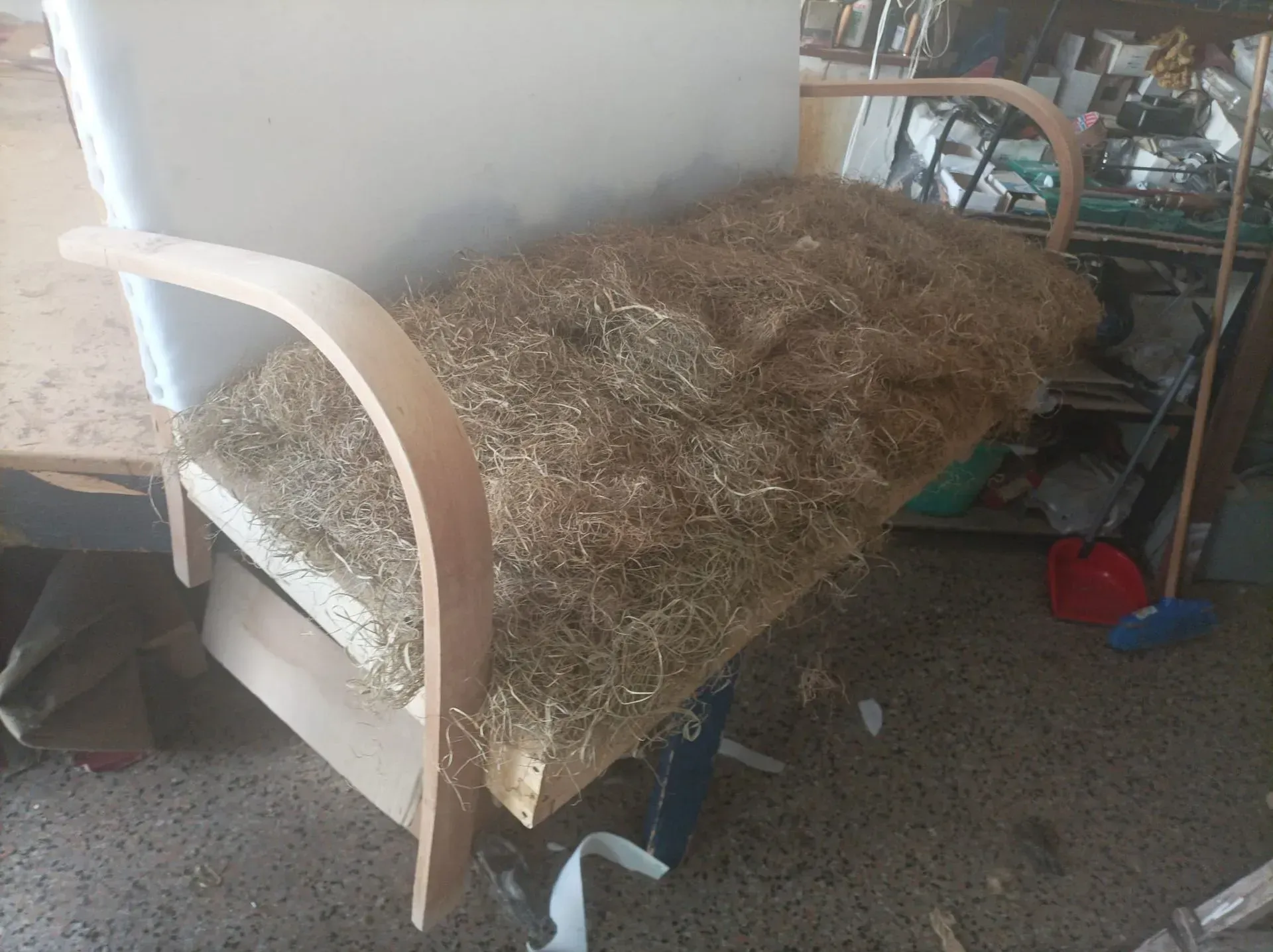 Una sedia in legno parzialmente costruita con un cuscino riempito di paglia, ambientata in un ambiente da laboratorio.