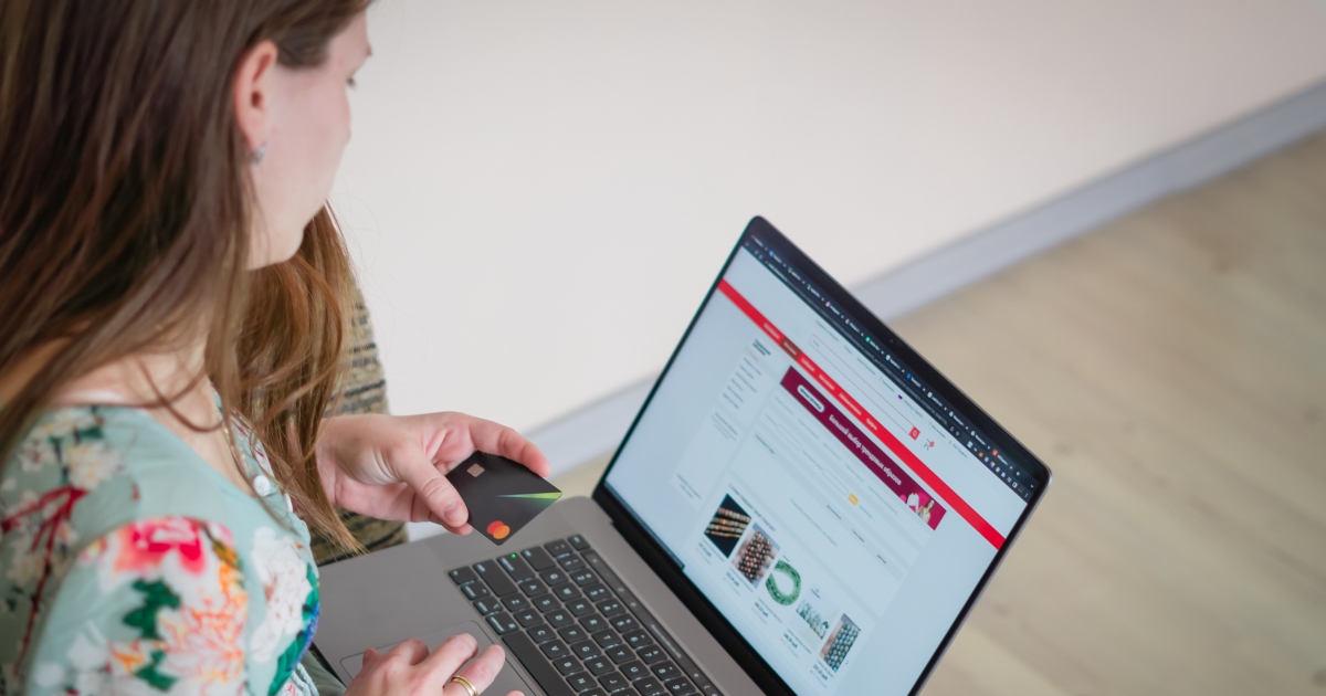 Woman analyzing product options on an e-commerce site while holding a credit card, reflecting buying behavior.